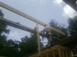 Carpenter setting a ridge beam over a new addition frame — Ice Dam Removal by Roofing Brothers in Greendale