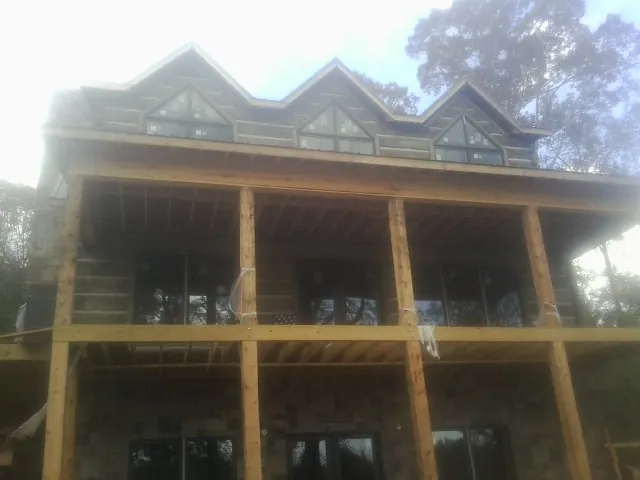 Dormers and porch framing on a large log home under construction — Roof Coating work by our crew in Greendale