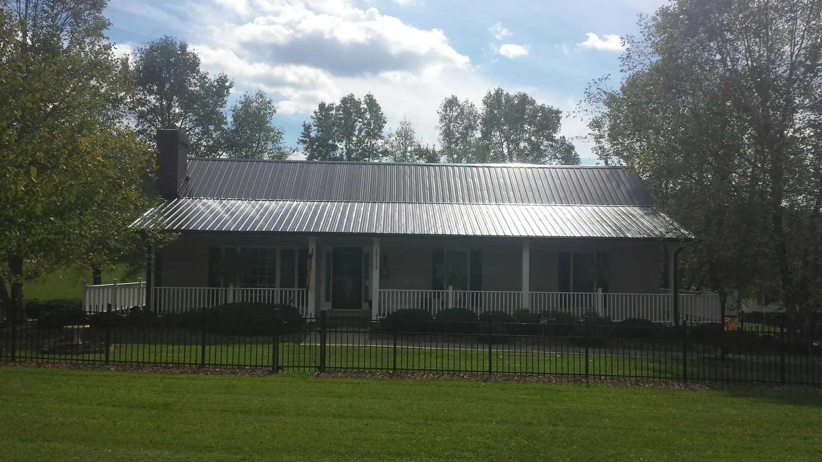 Gray metal roof on a brick ranch with a full width front porch — Gutter Guard Installation work by our crew in Greendale
