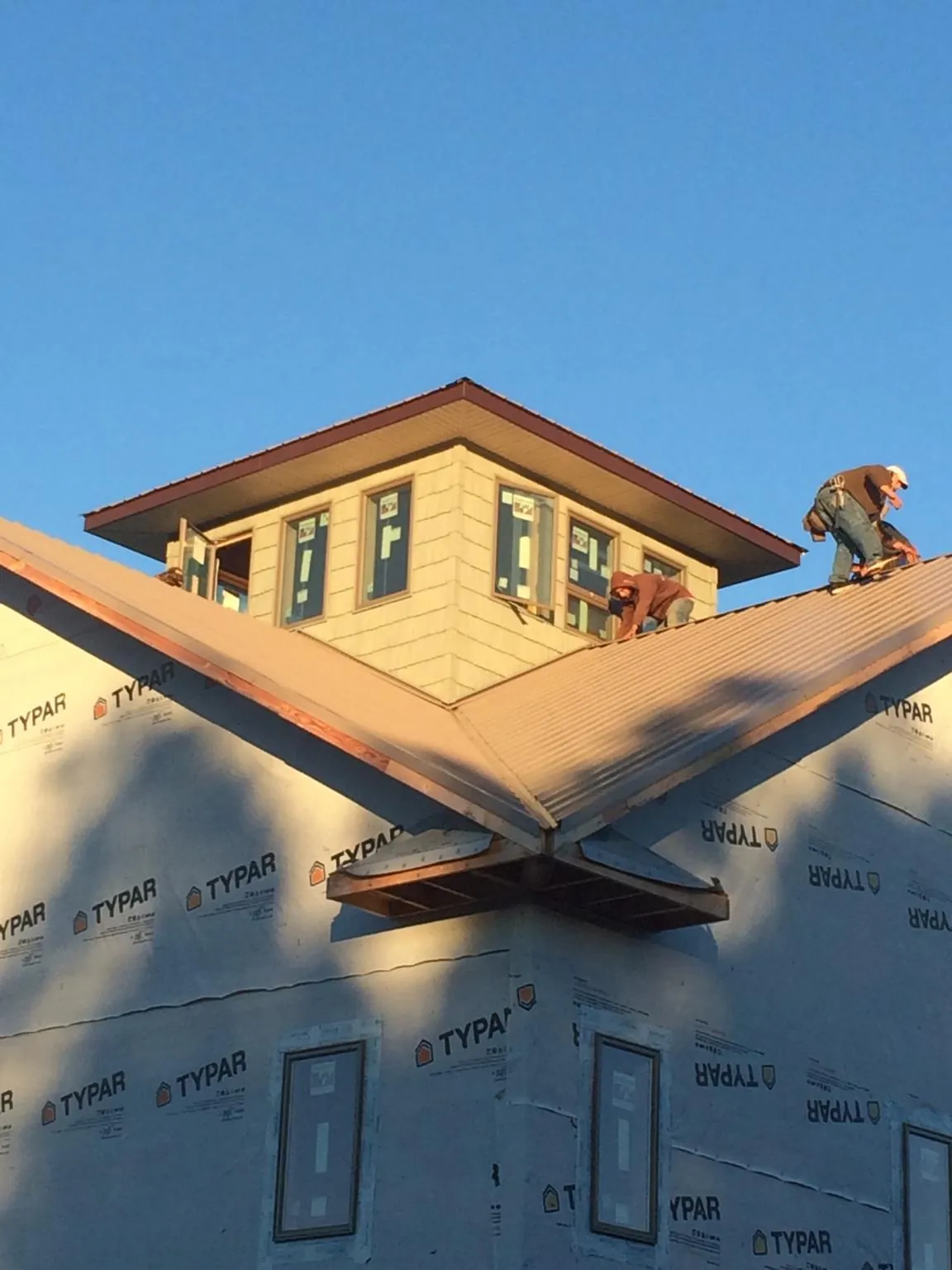 Roofers working around a rooftop cupola on a new metal roof at sunset — Roof Waterproofing in Greendale by Roofing Brothers